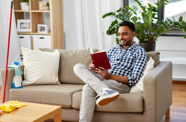 man reading book and resting after home cleaning - Photo, Image