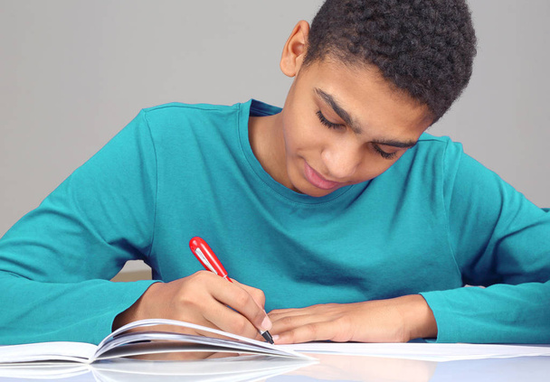Teenager in blauer Bluse schreibt in Notizbuch - Foto, Bild