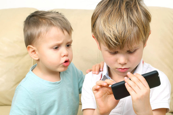 két kisfiú pillantást a smartphon - Fotó, kép
