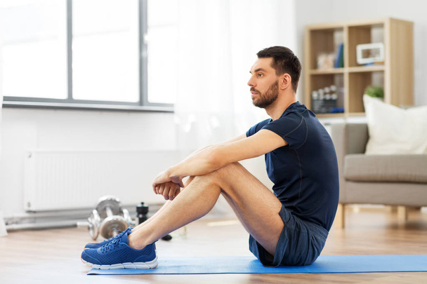 man resting on exercise mat at home - Φωτογραφία, εικόνα