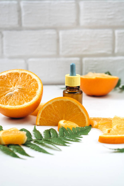 Natural cosmetic skincare. Serum with vitamin C in brown glass bottles, leaf fern and orange in a cut. High dose vitamin c synthetic for skin. Organic Natural Cosmetics Concept - Fotoğraf, Görsel