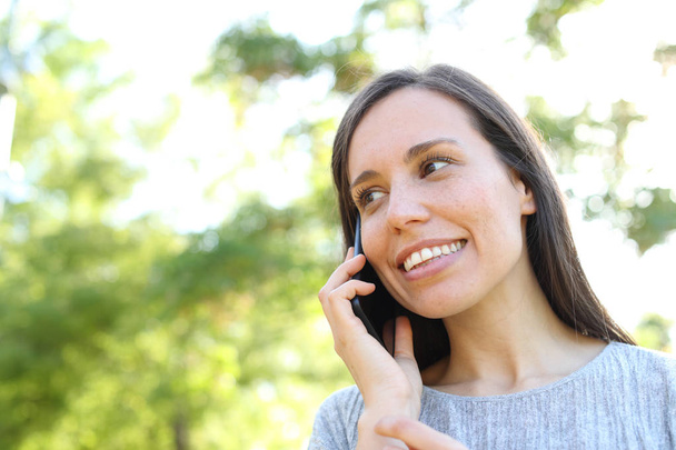 Счастливая женщина разговаривает по телефону в парке
 - Фото, изображение