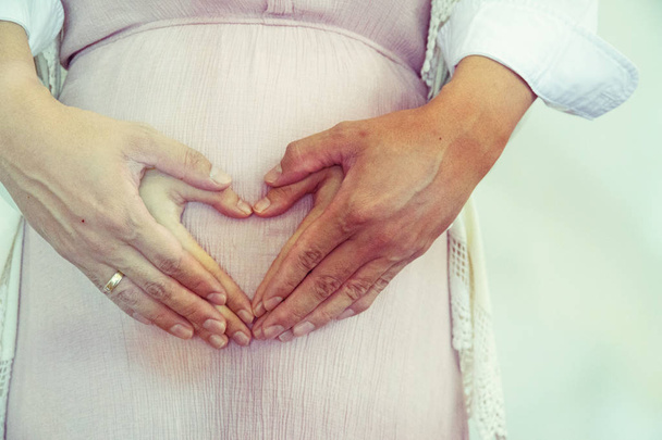 Κοντινό-up έγκυος γυναίκα με τον άντρα και το χέρι αγάπη πινακίδα. - Φωτογραφία, εικόνα