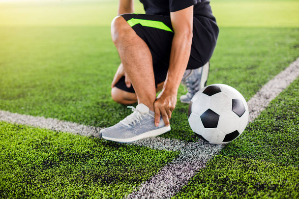 Bola de futebol em relva artificial verde com jogador de futebol está sentado
  - Foto, Imagem