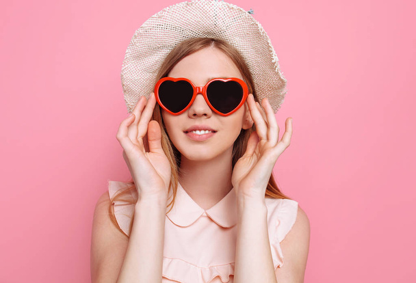 Portrait of a cheerful girl in a summer hat and heart-shaped sunglasses waiting for a vacation - Foto, Imagem