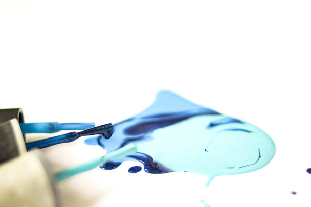 Blue nail Polish shellac varnish stain with tassels dripping drops close up on white background. - Valokuva, kuva