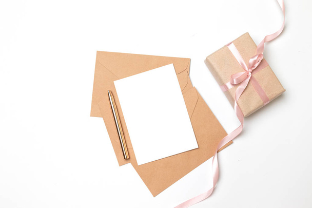 Χάρτινο φάκελο με κενό φύλλο και κουτί δώρου έκπληξη με ροζ κορδέλα σε γκρι φόντο - Φωτογραφία, εικόνα