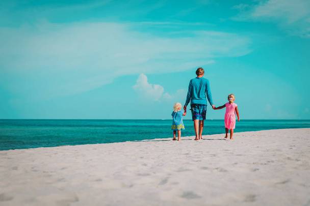 père et deux petites filles marchent sur la plage
 - Photo, image