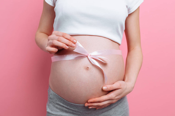 An image of a pregnant woman with a pink ribbon on her belly - Photo, Image