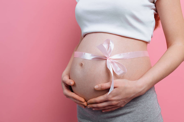 Зображення вагітної жінки з рожевою стрічкою на животі
 - Фото, зображення