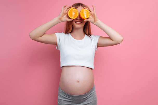 Beautiful pregnant woman with orange fruit - Foto, Imagen