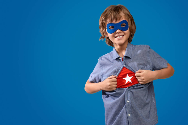 fröhlicher Junge zeigt Superheldenkostüm - Foto, Bild