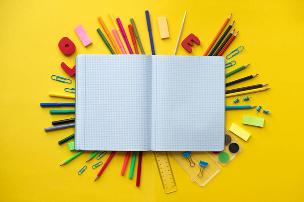 Notebook with school supplies on yellow background with copy space - Foto, afbeelding