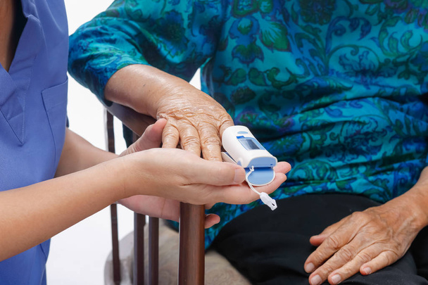Caregiver monitoring oxygen saturation at fingertip of elderly w - Photo, Image