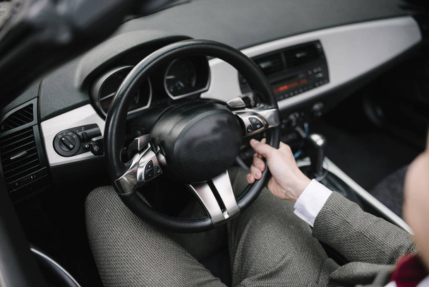 A man in a suit sits behind the wheel of a car. - Fotó, kép