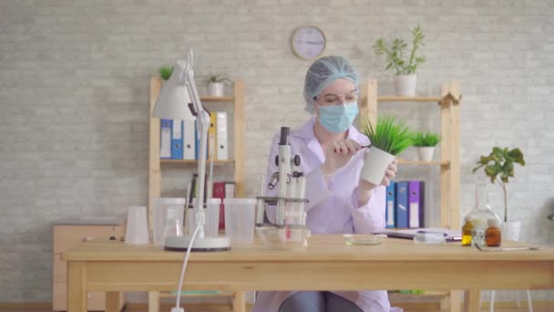 Woman laboratory assistant conducts a study of the plant with a microscope in a modern laboratory - Video, Çekim