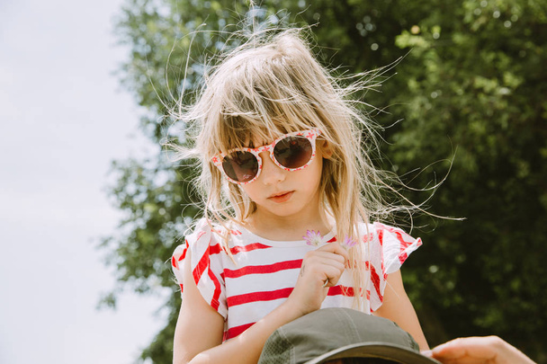 Маленькая девочка в солнечных очках смотрит вниз
 - Фото, изображение