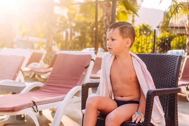 A five-year-old child sits on a sunbed - Valokuva, kuva
