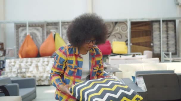 afroamerikai nő egy afro frizura kiválasztja a párnák egy bútoráruház - Felvétel, videó