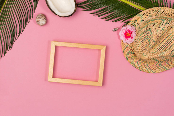 Stylish summer composition with photo frame, green leaves, hat and coconut on a pink pastel background. Artwork mockup with copy space - Foto, Imagem