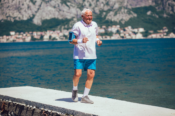 счастливый пожилой человек делает утреннюю зарядку на пляже
 - Фото, изображение