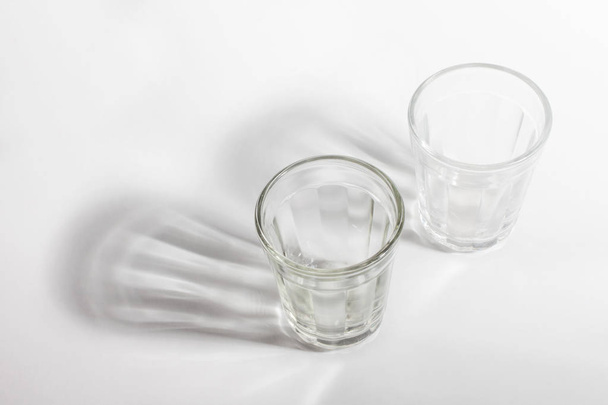 close up view of empty glasses and shadows on light background - Foto, Imagem
