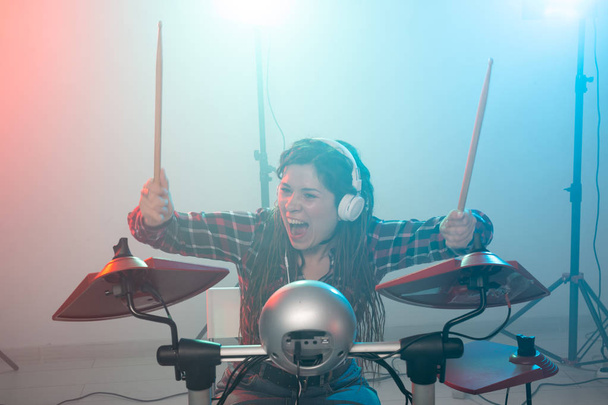Electronic drum set, music and hobby concept - young woman drummer playing in headphones - Photo, Image