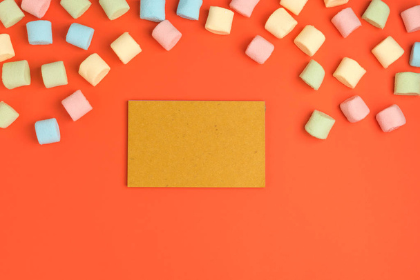 Coral paper background with marshmallow and blank notepad. Place for your text. Cozy sweet background - 写真・画像