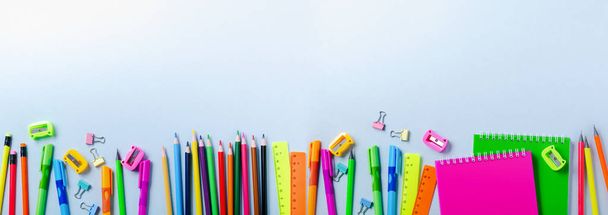 Notebook, colored pencils, ruler, pen, eraser, sharpener and more. School and office stationery on blue background. Banner Concept back to school. Top view. - Foto, Imagem