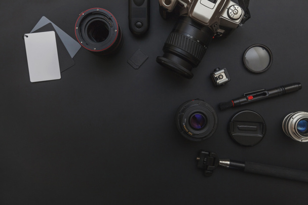 Fotograaf werkplek met DSLR camera systeem, camera reiniging kit, lens en camera accessoire op donkere zwarte tafel achtergrond - Foto, afbeelding