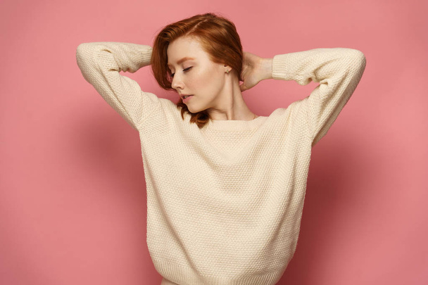 Young redhead girl with closed eyes holds her hair keeping her h - Фото, зображення