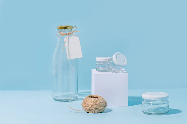 Glass bottle and jars with hank of twine over blue background. - Fotó, kép