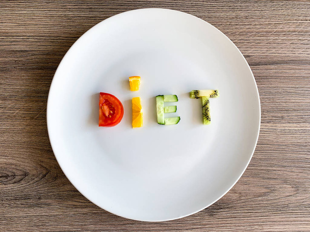 Word Dieta z plasterków warzyw w białym talerzu na tle drewna - Zdjęcie, obraz