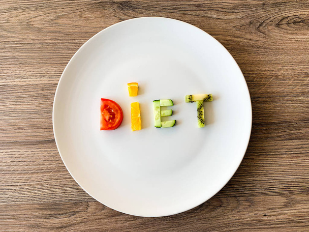 Слово DDT из скользящих овощей в белой тарелке на деревянном фоне
 - Фото, изображение