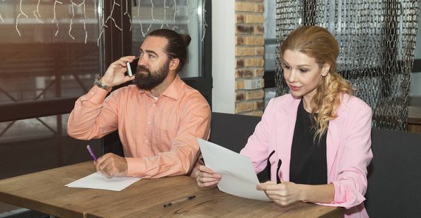 Work of the sales department in the office, registration of financial documents. Business people, a man talking on a smartphone and a woman reading a contract. - Foto, immagini