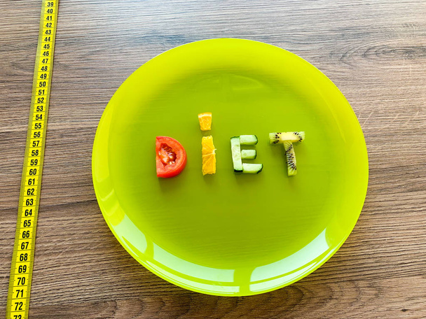 Word Dieta z plasterków warzyw w talerzu z pomiarem na tle drewna - Zdjęcie, obraz
