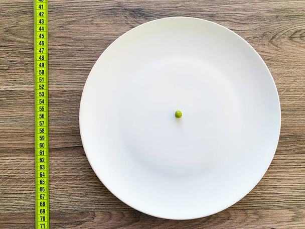 Διατροφή. Υποφέρει από ανορεξία. Περικομμένη εικόνα μπιζέλι σε λευκή πλάκα - Φωτογραφία, εικόνα