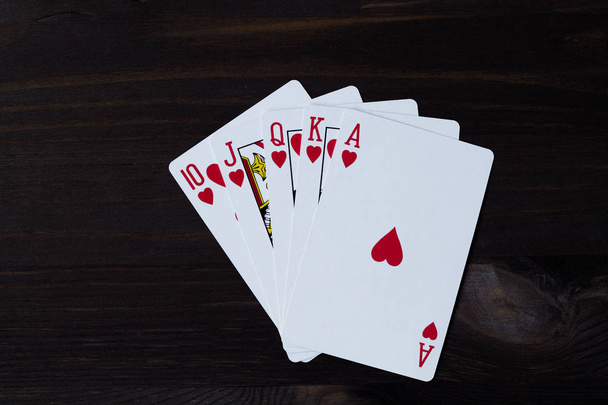 Spielkarten auf schwarzem Hintergrund. Royal Flush in den Herzen - Foto, Bild