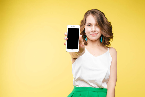 Девушка показывает мобильный телефон на камеру с шокированным выражением лица
. - Фото, изображение
