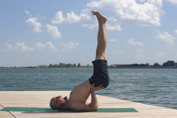 Man doing yoga on a wooden floor in the nature - Foto, Bild