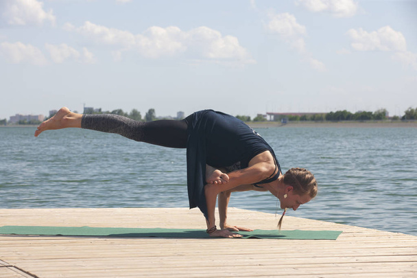 Beautiful woman practicing Yoga by the lake - Valokuva, kuva