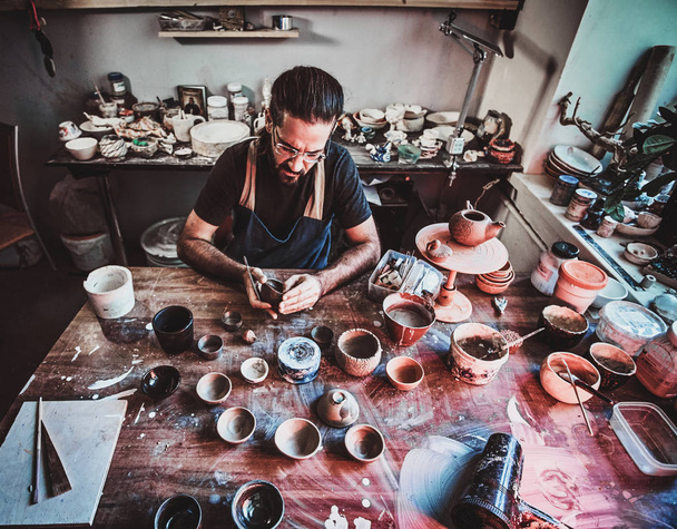 Entusiastici Potter in glazen in zijn eigen atelier is workig op een nieuwe handgemaakte theepot. - Foto, afbeelding