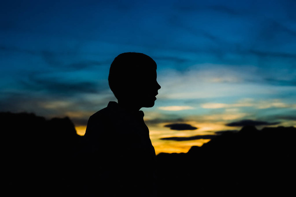 Dark backlit silhouette of a happy and smiling child at dusk, wi - Photo, Image
