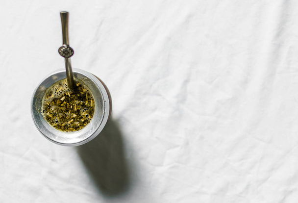 Yerba maté thee in een kalebas kalebas tegen witte achtergrond. Selectieve focus - Foto, afbeelding