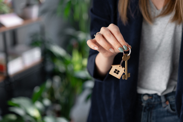 Concept of renting an apartment. House key in womans hands. Young woman. Modern light lobby interior. Real estate, hypothec, moving home or renting property. - Photo, Image