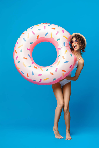 Funny black girl in swimsuit biting donut shaped swim ring - Foto, Imagem