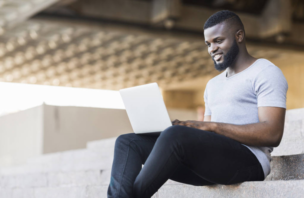 Uśmiechnięty African American facet kodowania na swoim laptopie - Zdjęcie, obraz