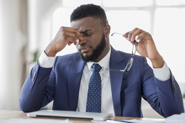 Homme d'affaires africain frustré massant son nez au bureau
 - Photo, image