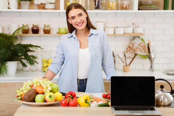 Donna che cucina insalata mostrando computer portatile con schermo vuoto
 - Foto, immagini