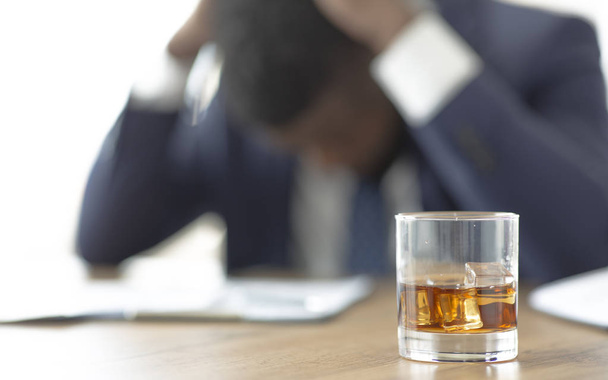 Zdesperowany afrykański biznes cierpiący w miejscu pracy ze szklanką whisky - Zdjęcie, obraz